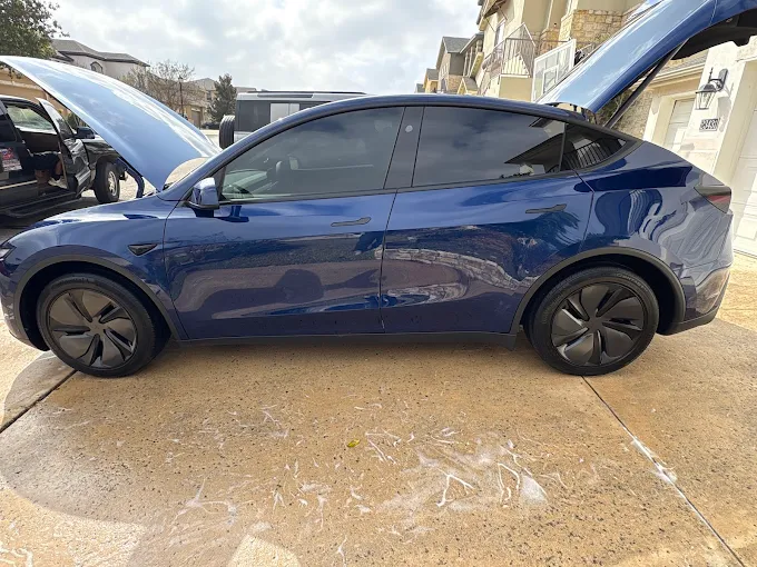 Dark blue Tesla Model Y in a San Antonio driveway after paint enhancement and 3-year ceramic coating by Bluebird Mobile Detailing